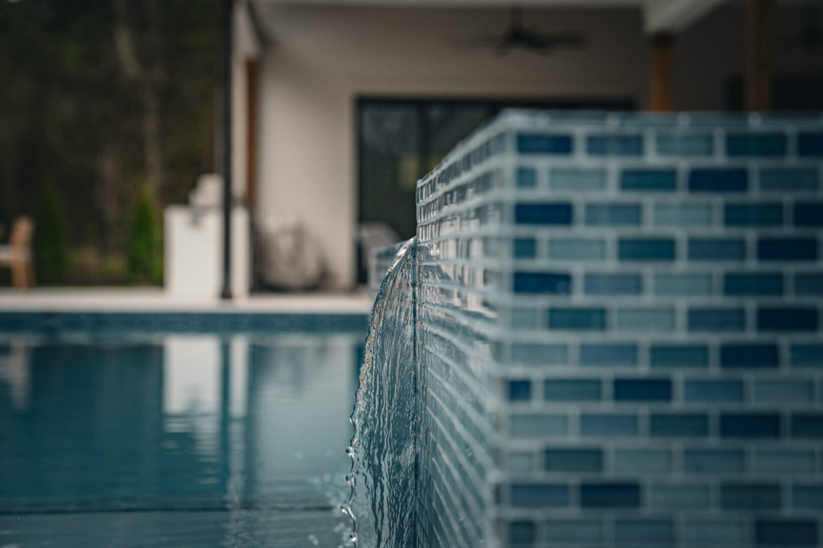 Water gently flowing from a tiled pool edge into the pool below.