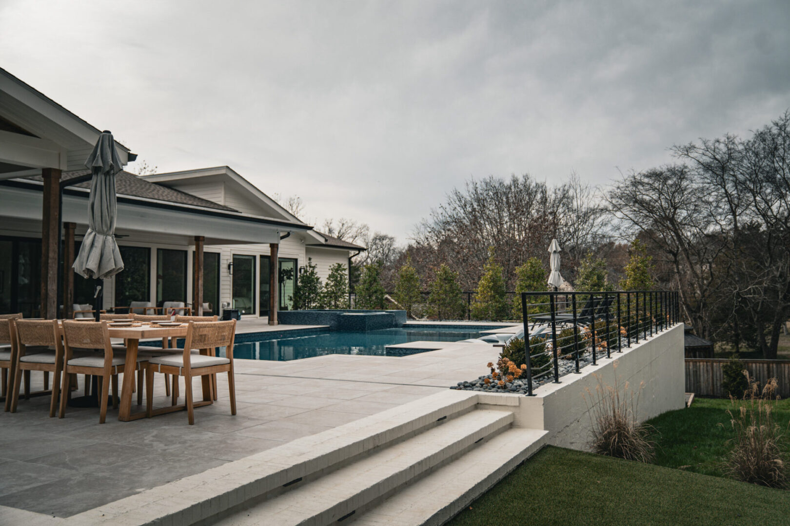 Modern outdoor patio with pool and seating under cloudy sky.