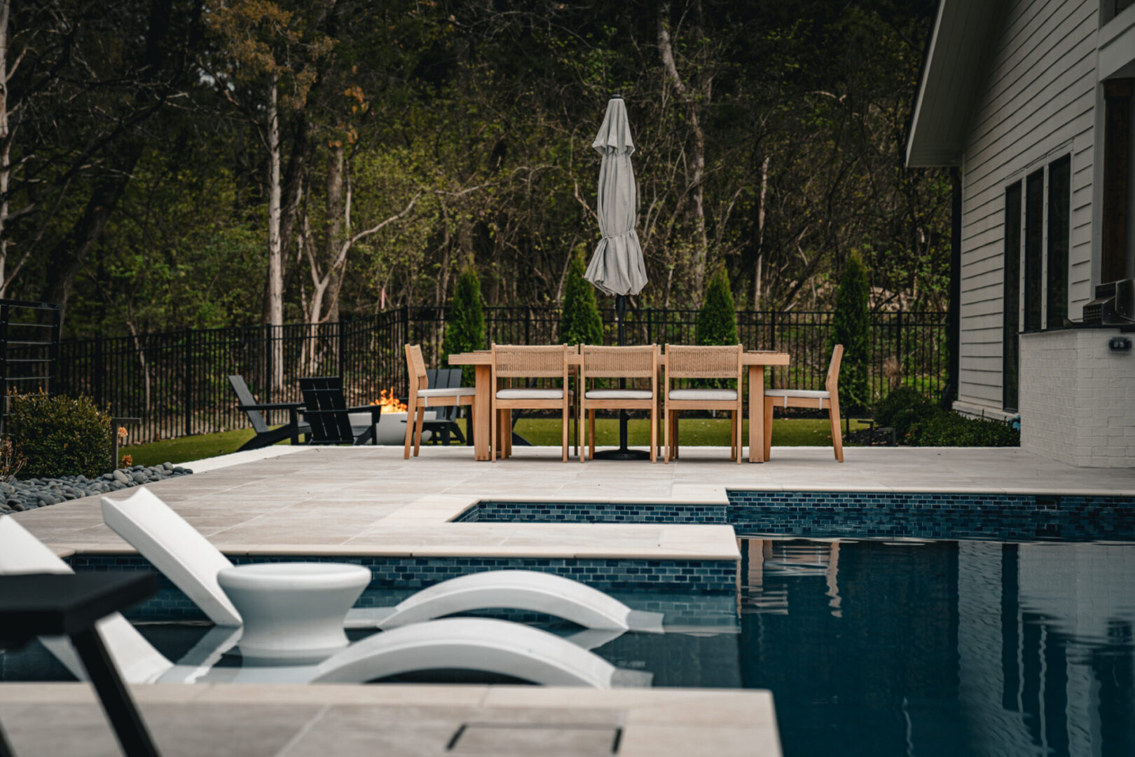 Modern poolside lounge chairs and outdoor dining set in a serene backyard.