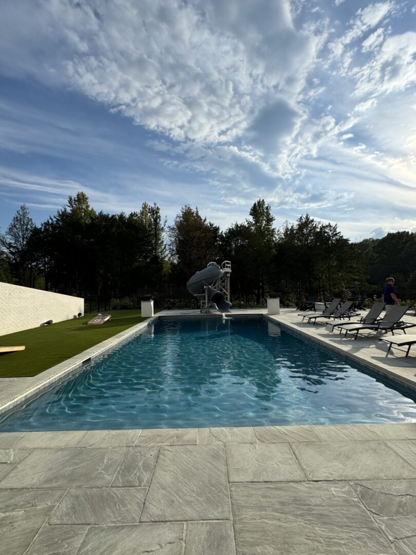 Person mid-air jumping into a swimming pool on a sunny day.