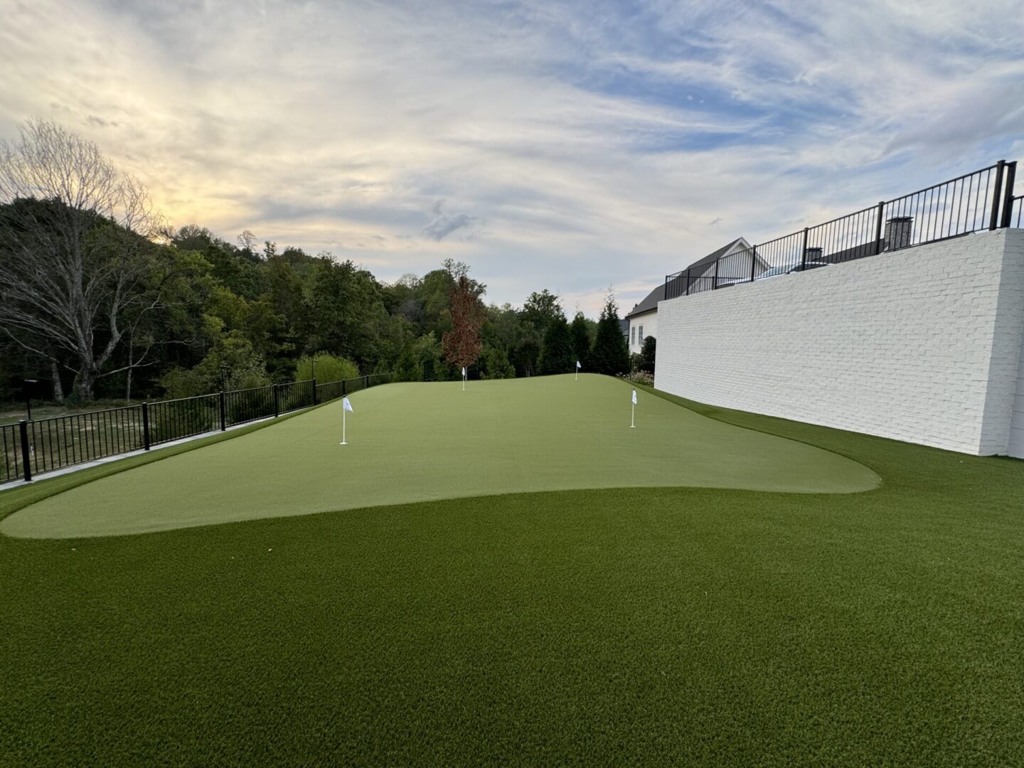 A green artificial turf golf practice area with a putting hole and flag.