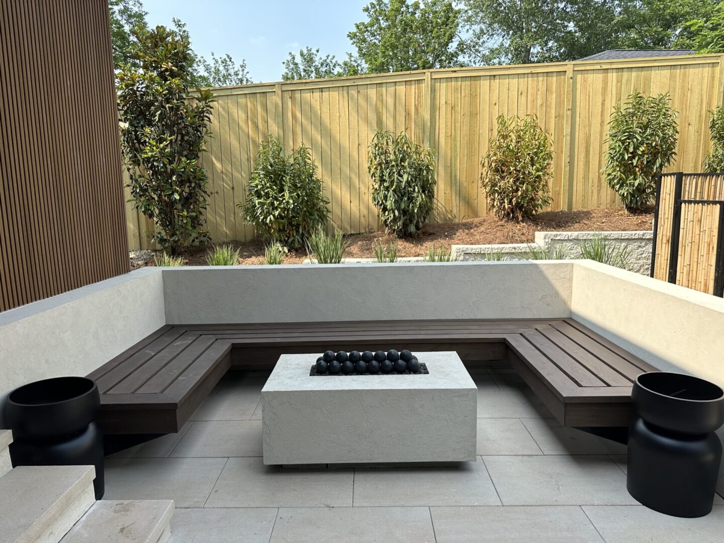 Modern outdoor seating area with a fire pit and wooden bench.