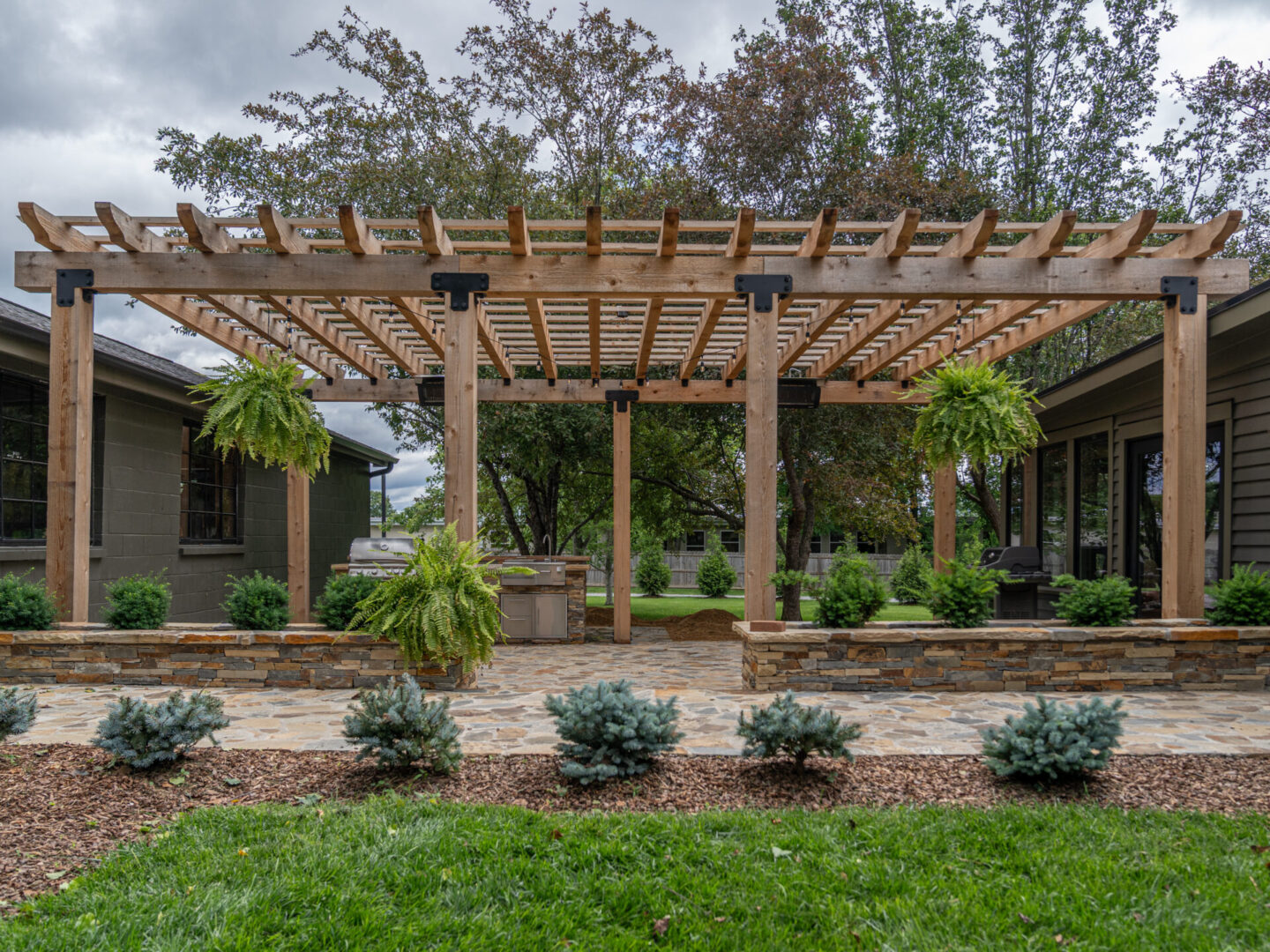 A backyard pergola with hanging plants and landscaped garden beds.